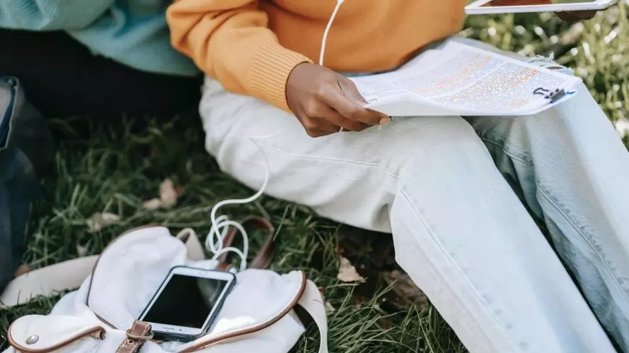Student holding a research paper and a tablet